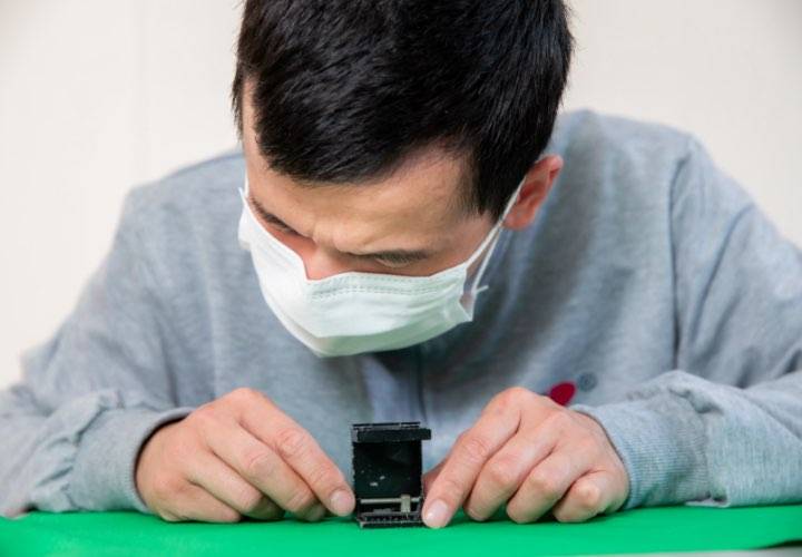 A worker uses a vernier caliper to measure the gauge of a fabric.