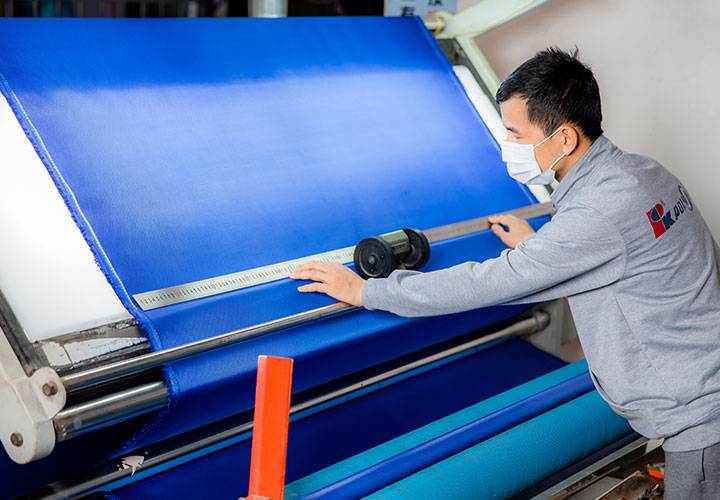 A worker uses a machine to cut fabric.